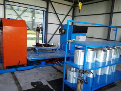 There is one set of GRE pipe winding machine in the warehouse, and many rolls of yarn are on a blue frame.